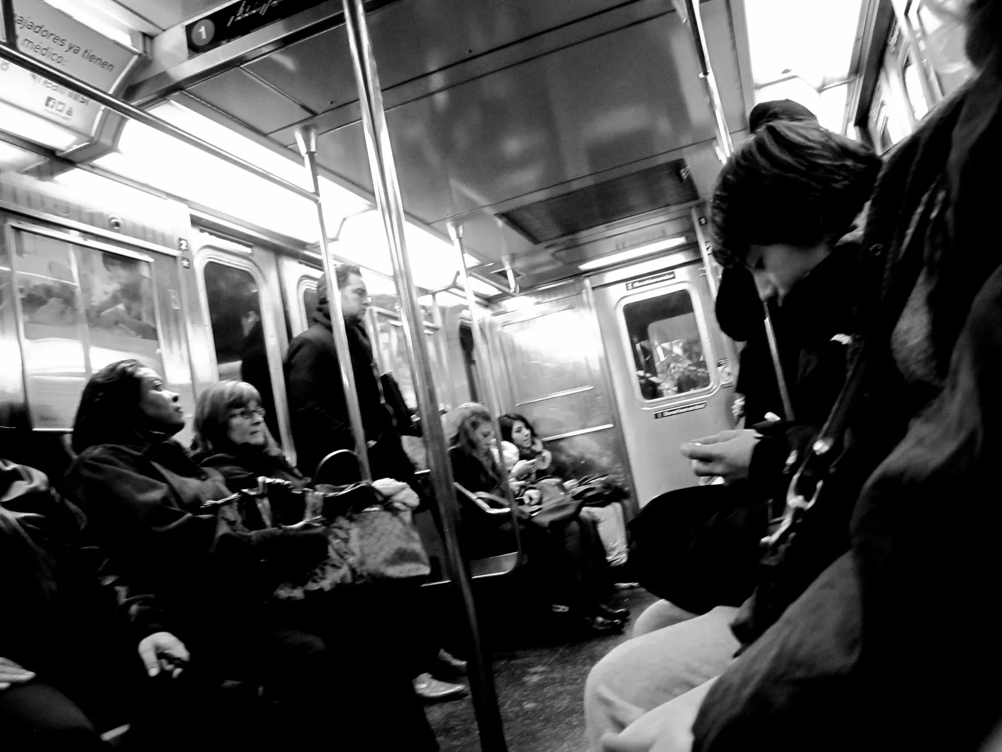 Black and white photo of riders inside a New York subway car